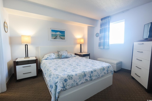 bedroom featuring dark carpet and a textured ceiling