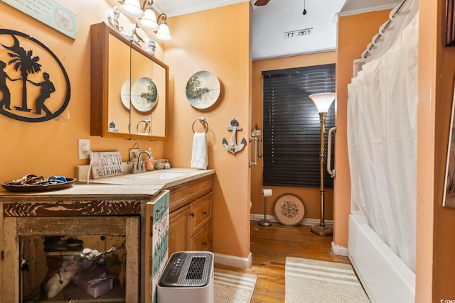 bathroom featuring hardwood / wood-style flooring, ornamental molding, vanity, and shower / bathtub combination with curtain