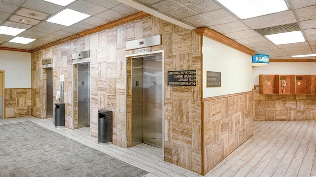 interior space featuring elevator, crown molding, and a paneled ceiling