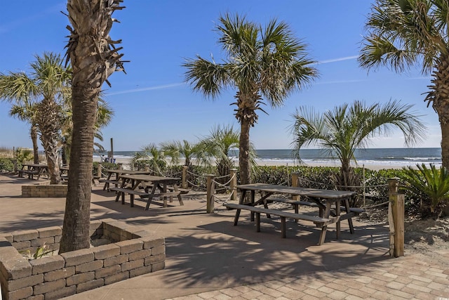 surrounding community with a water view, a patio area, and a view of the beach