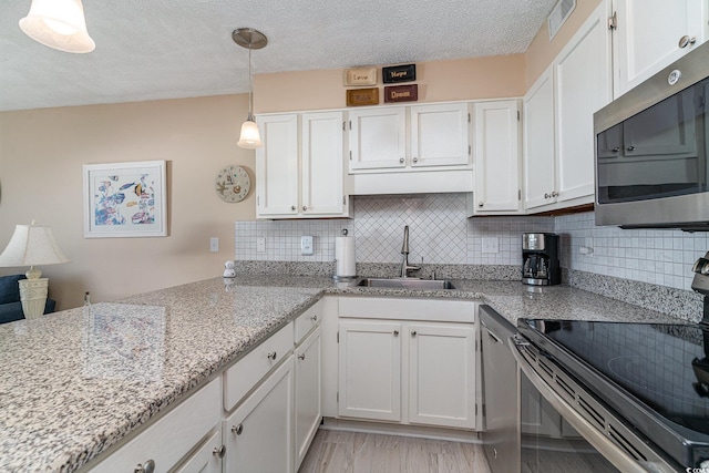 kitchen featuring sink, white cabinetry, hanging light fixtures, electric range, and light stone countertops