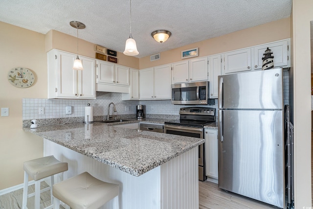 kitchen with sink, a breakfast bar area, white cabinetry, kitchen peninsula, and stainless steel appliances