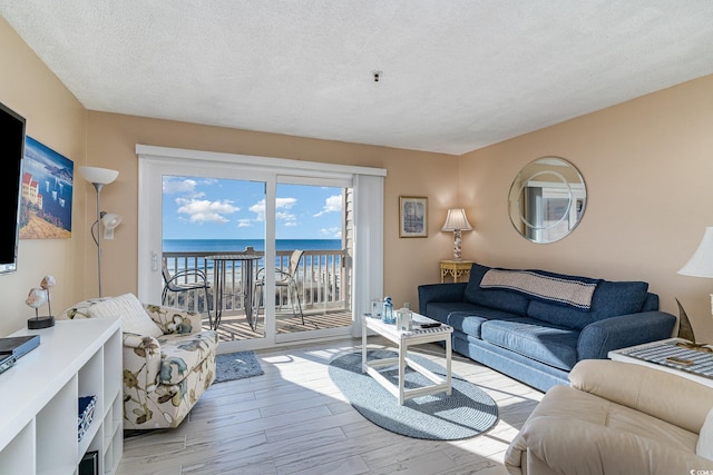 living room featuring a water view, a textured ceiling, and light wood-type flooring