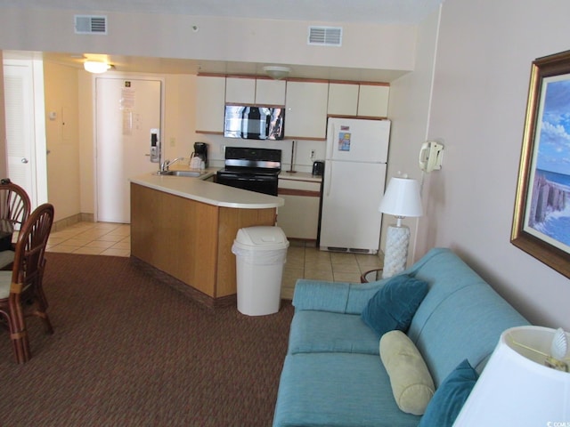 kitchen with stainless steel microwave, visible vents, black range with electric cooktop, light countertops, and freestanding refrigerator