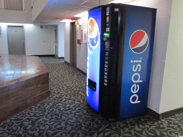 corridor with a drop ceiling, carpet, and baseboards