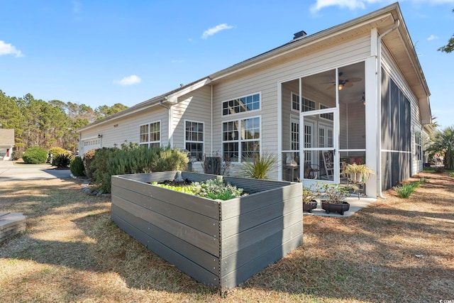 view of side of property featuring a garage, a sunroom, and ceiling fan