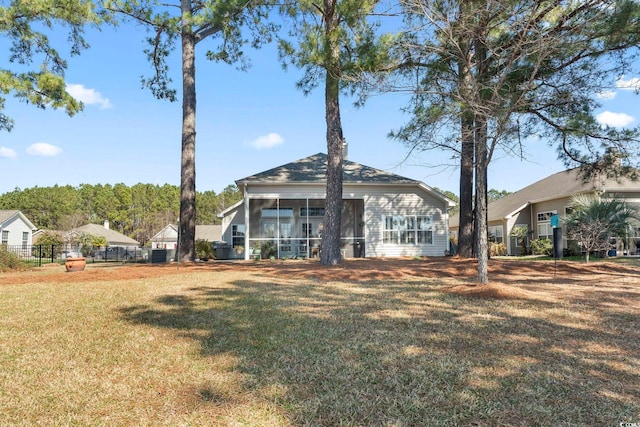 rear view of house featuring a yard and a sunroom