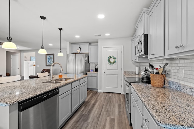 kitchen featuring a center island with sink, decorative light fixtures, sink, and stainless steel appliances