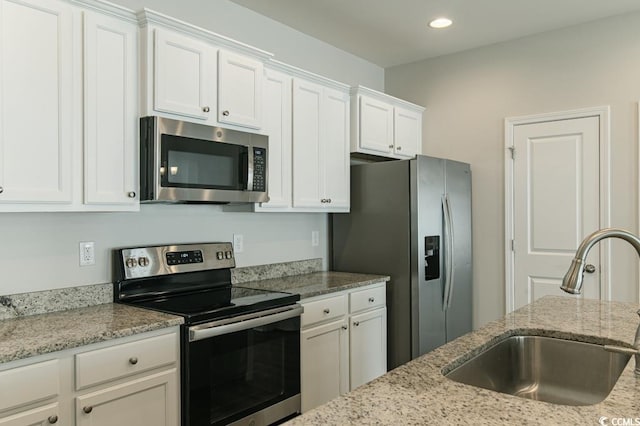 kitchen featuring sink, stainless steel appliances, white cabinets, and light stone counters