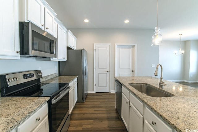 kitchen with appliances with stainless steel finishes, light stone counters, white cabinets, pendant lighting, and sink