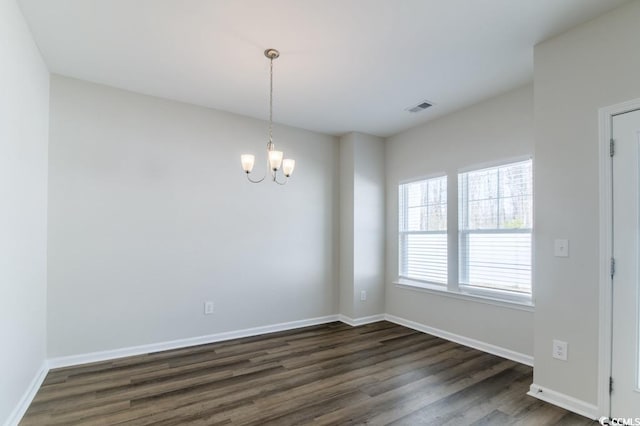 empty room with an inviting chandelier and dark hardwood / wood-style flooring