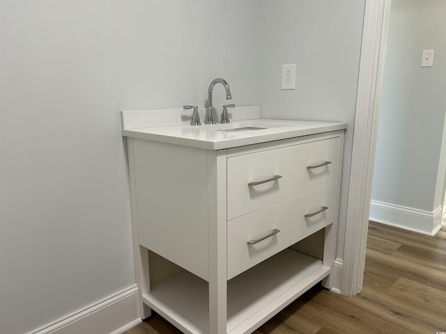 bathroom with baseboards, wood finished floors, and vanity