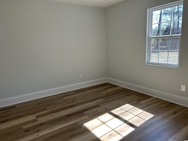 spare room featuring dark wood-style floors and baseboards