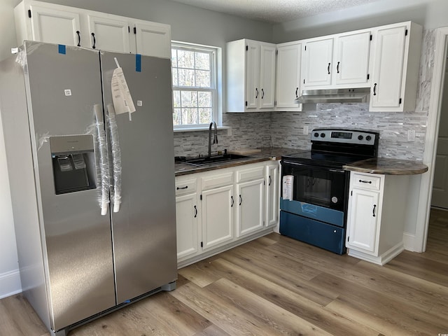 kitchen with black / electric stove, dark countertops, stainless steel fridge, and under cabinet range hood