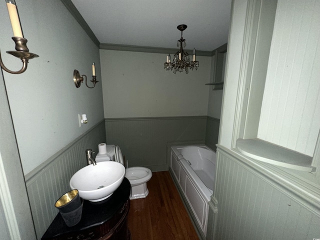 bathroom with a chandelier, hardwood / wood-style flooring, a washtub, toilet, and crown molding