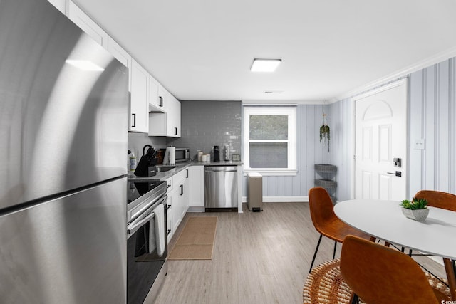 kitchen featuring crown molding, light wood-type flooring, white cabinets, and appliances with stainless steel finishes