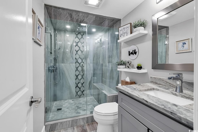 bathroom featuring vanity, a shower with door, and toilet