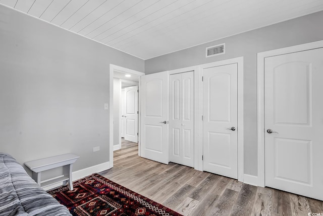 bedroom with light wood-type flooring and wooden ceiling