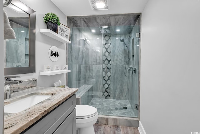 bathroom with toilet, vanity, wood-type flooring, and a shower with shower door