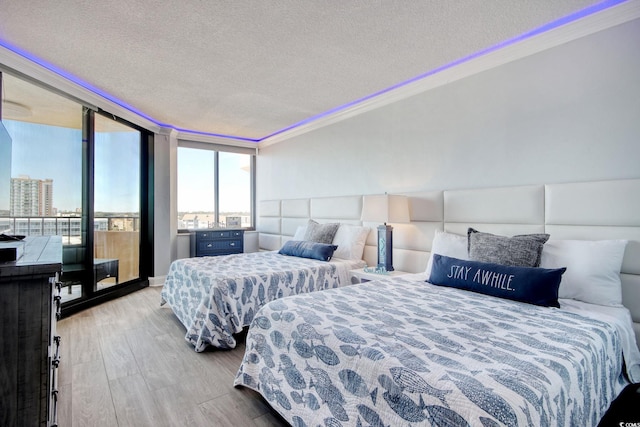 bedroom featuring ornamental molding, light hardwood / wood-style flooring, and a textured ceiling