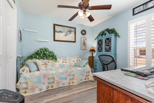 bedroom with light hardwood / wood-style flooring, ceiling fan, and a closet