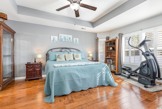 bedroom with a tray ceiling, ceiling fan, and hardwood / wood-style flooring