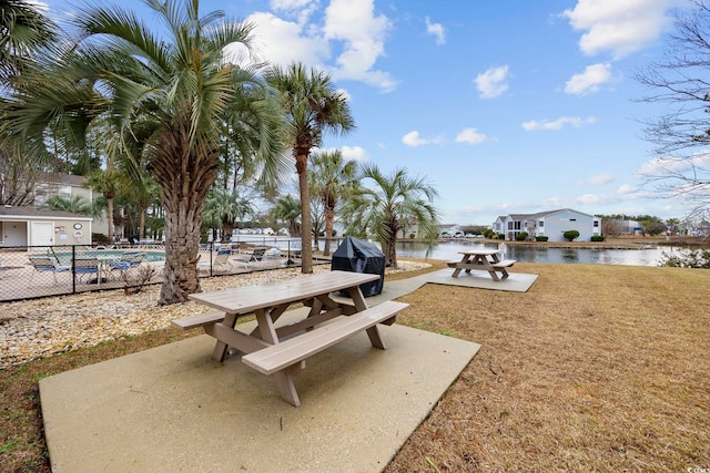 view of community featuring a water view, fence, a pool, and a patio