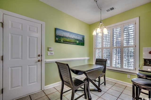 tiled dining room with a textured ceiling and a notable chandelier