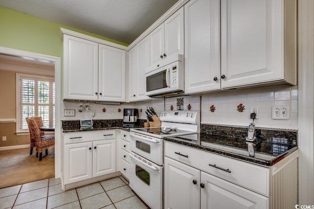 kitchen with light tile patterned floors, white appliances, white cabinetry, and tasteful backsplash