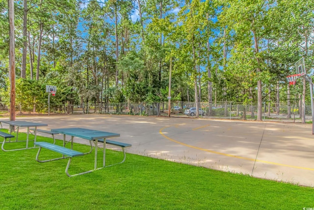 view of community with community basketball court, fence, and a yard