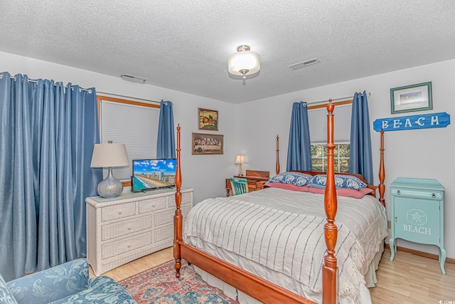 bedroom featuring light wood-type flooring, visible vents, and a textured ceiling