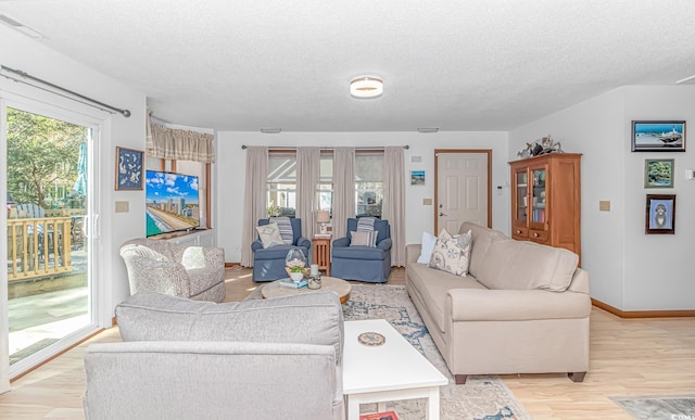 living room featuring light wood-type flooring, plenty of natural light, and a textured ceiling