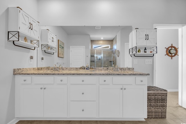 bathroom with baseboards, double vanity, a sink, tile patterned flooring, and a shower stall