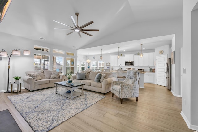 living room with ceiling fan, plenty of natural light, and light wood-style flooring