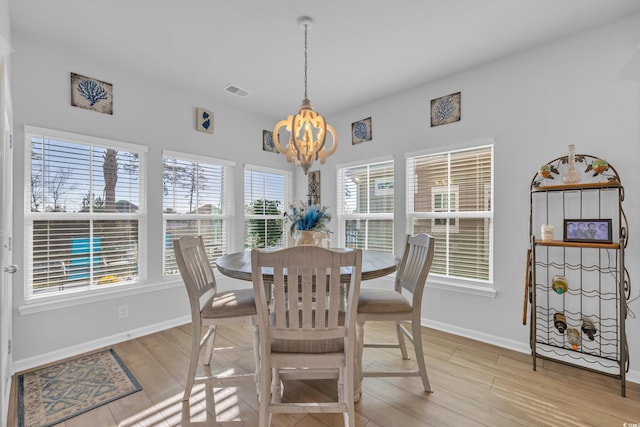 dining area with a notable chandelier, visible vents, baseboards, and light wood finished floors