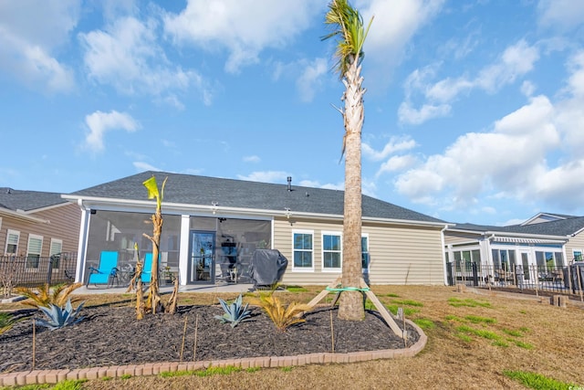 rear view of house featuring a patio, fence, a sunroom, and roof with shingles