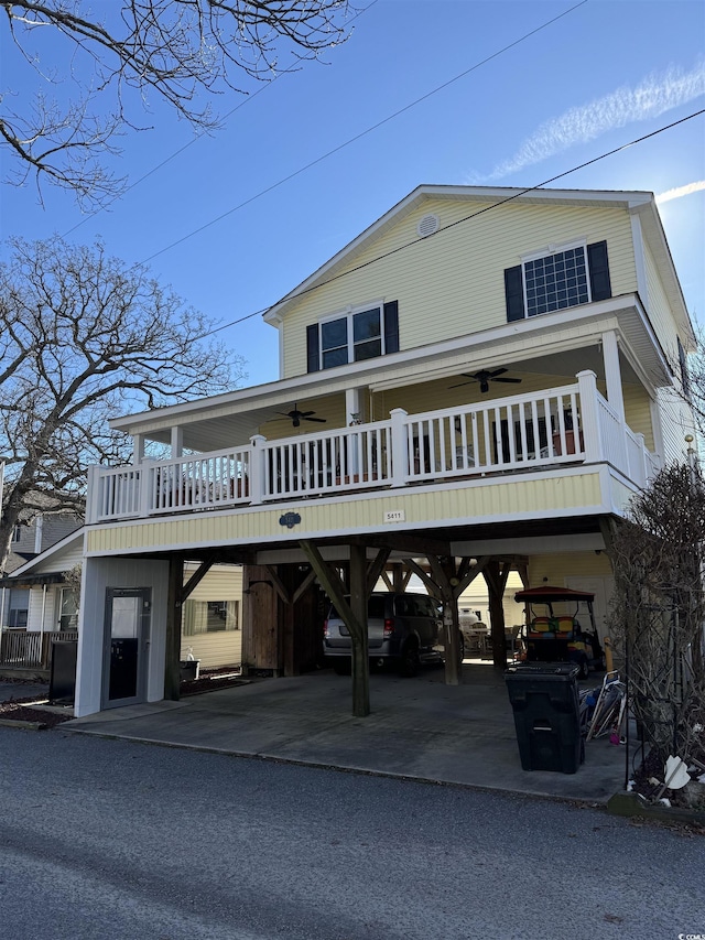 view of front of home with a carport, driveway, a balcony, and a ceiling fan