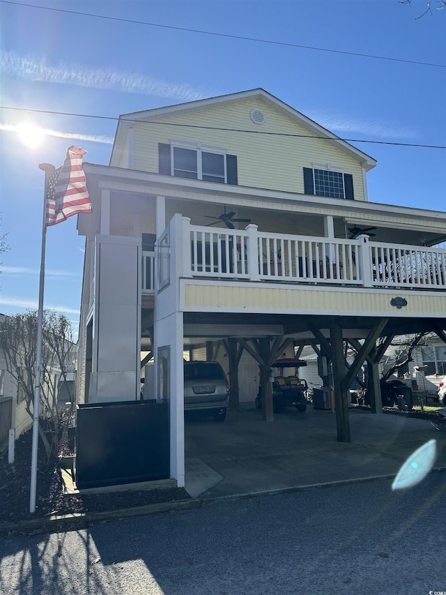 coastal home with ceiling fan, a carport, and a balcony