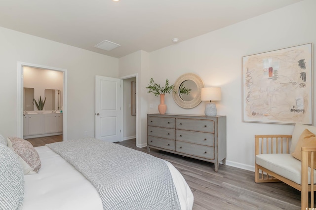 bedroom featuring ensuite bath, light wood-style flooring, and baseboards