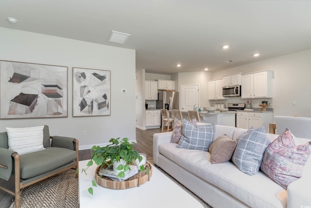 living area with baseboards, dark wood-type flooring, and recessed lighting