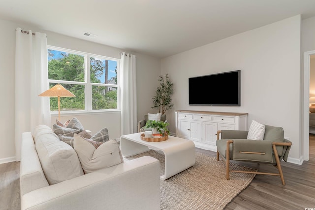 living room featuring light wood-style floors, visible vents, and baseboards