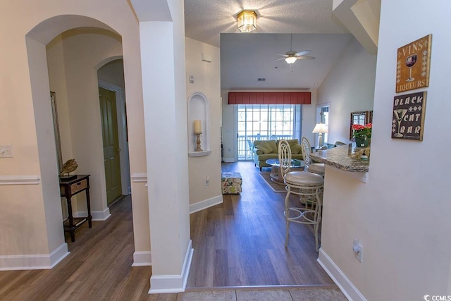 hallway featuring vaulted ceiling, a textured ceiling, and dark hardwood / wood-style floors