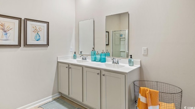 full bathroom featuring double vanity, baseboards, a sink, and a stall shower
