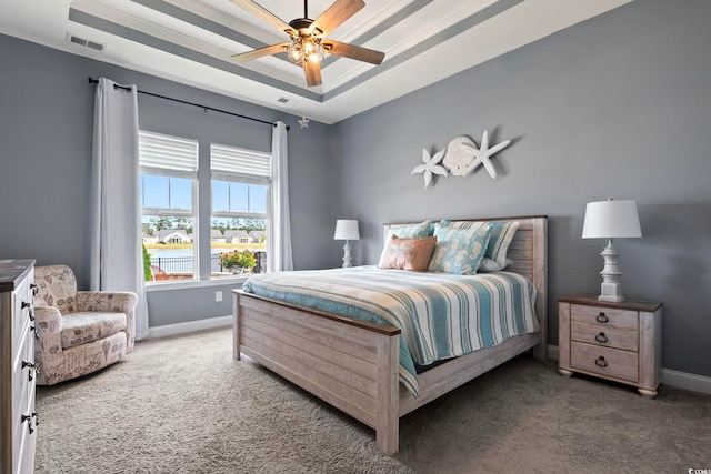 carpeted bedroom with ceiling fan and a raised ceiling