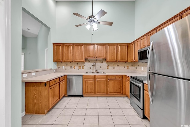 kitchen featuring appliances with stainless steel finishes, sink, backsplash, and a high ceiling