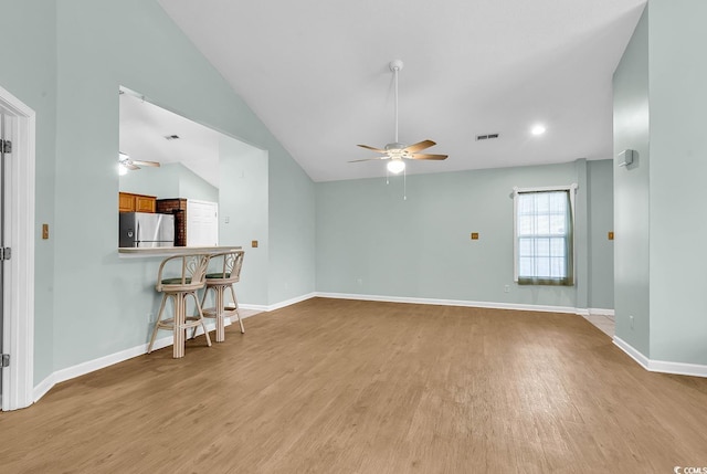 living room with ceiling fan, light hardwood / wood-style flooring, and vaulted ceiling