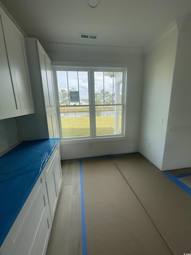 unfurnished dining area with crown molding and a water view