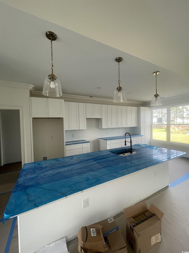 kitchen featuring a sink, white cabinetry, ornamental molding, a center island, and pendant lighting
