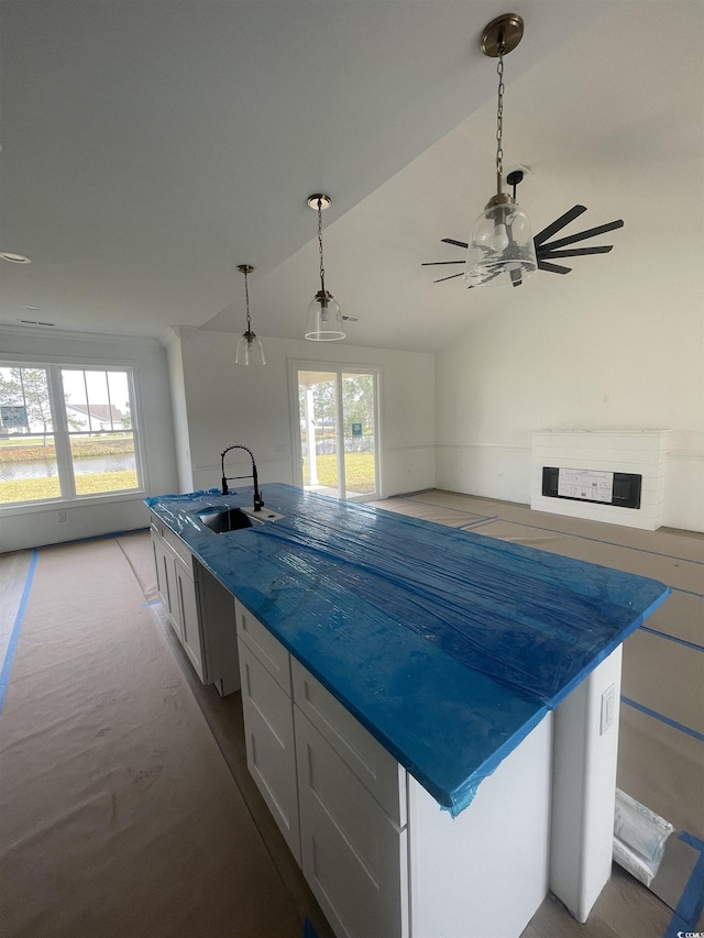 kitchen with a sink, a large island, lofted ceiling, ceiling fan, and dark countertops
