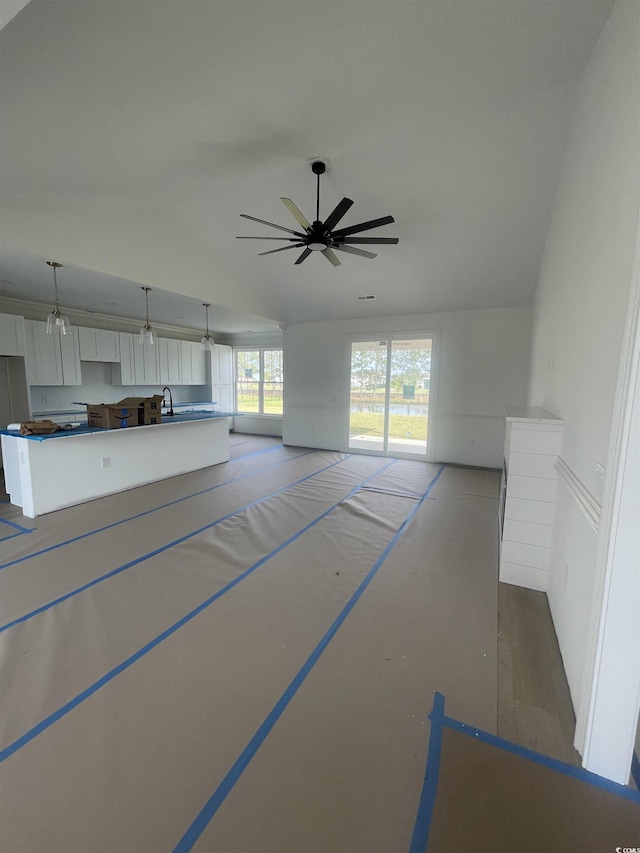 unfurnished living room with ceiling fan and vaulted ceiling